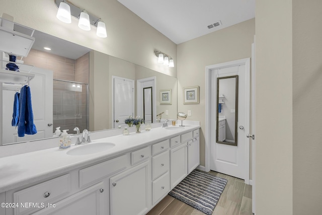 bathroom featuring a shower with shower door and vanity