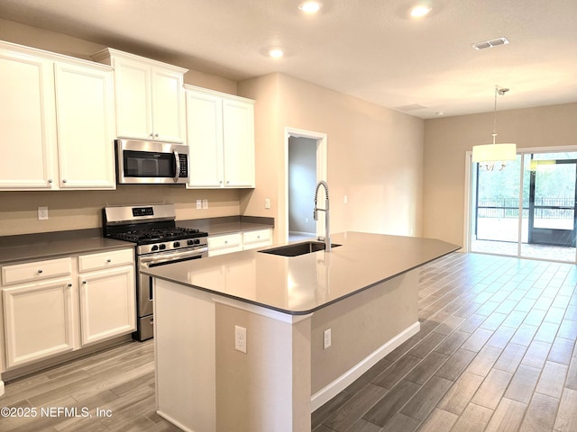 kitchen with decorative light fixtures, sink, a kitchen island with sink, stainless steel appliances, and white cabinets