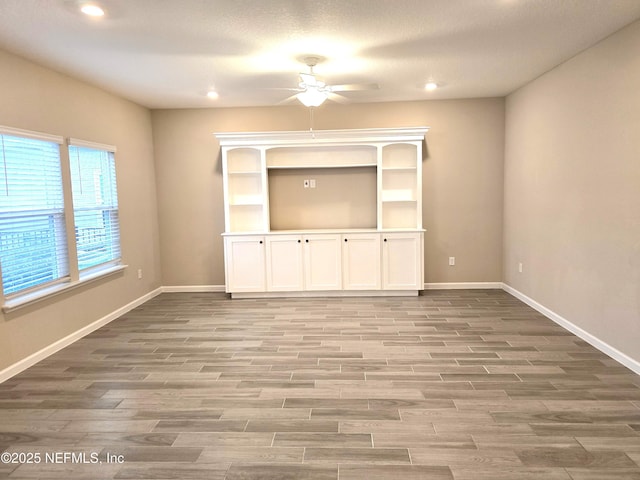 unfurnished living room with ceiling fan, wood-type flooring, and a textured ceiling