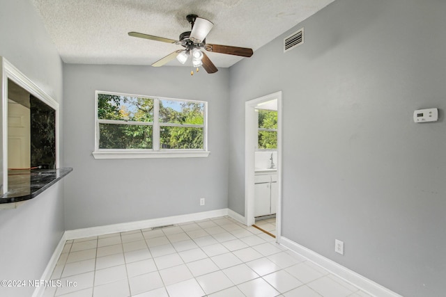 unfurnished room featuring a textured ceiling, ceiling fan, vaulted ceiling, and light tile patterned floors