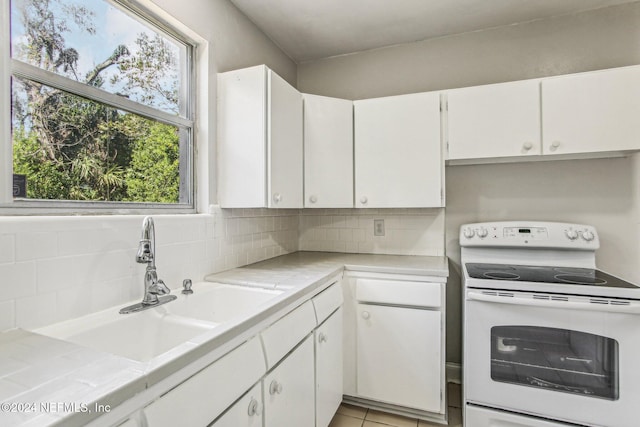 kitchen featuring backsplash, white cabinetry, light tile patterned floors, tile countertops, and white electric range