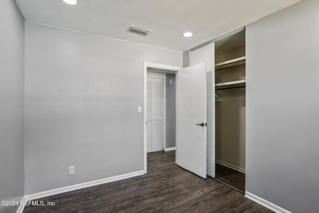 unfurnished bedroom with dark hardwood / wood-style floors and a closet