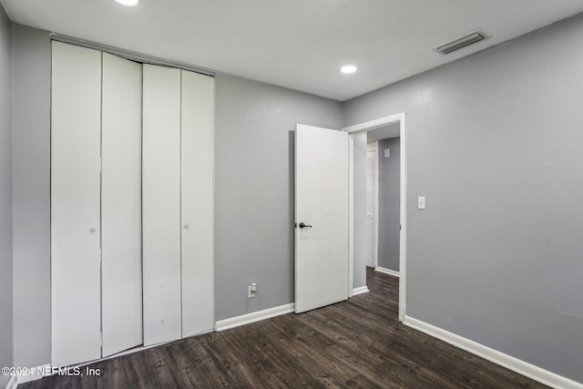 unfurnished bedroom with dark hardwood / wood-style floors and a closet