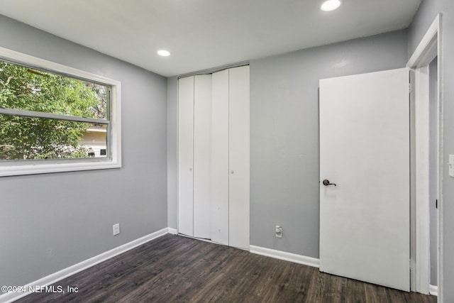 unfurnished bedroom featuring dark wood-type flooring and a closet