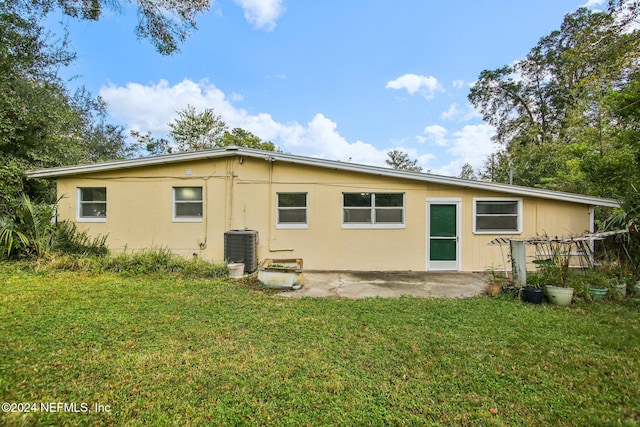 rear view of property featuring cooling unit and a lawn