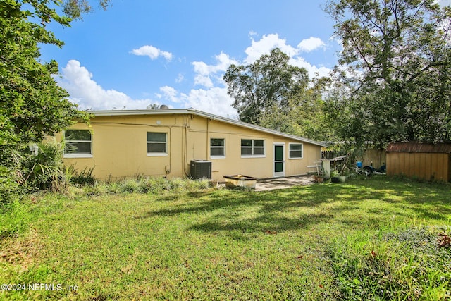 rear view of property featuring a patio, a lawn, central air condition unit, and a shed