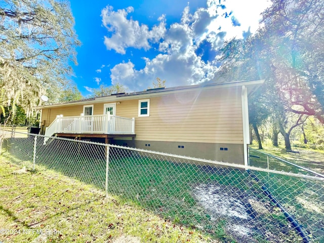 rear view of property featuring a deck and a lawn