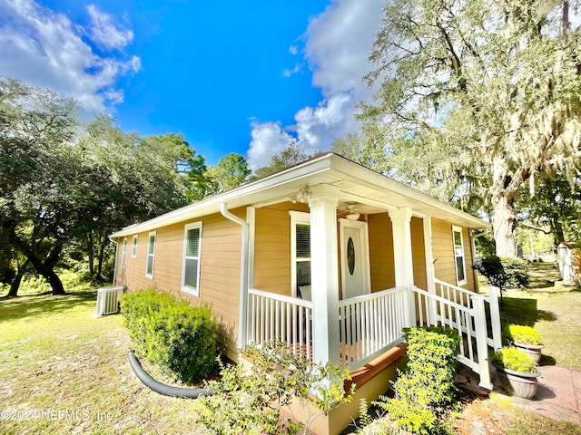 view of property exterior featuring a porch, central AC unit, and a lawn