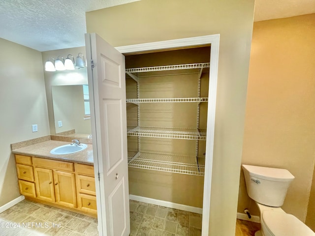 bathroom featuring toilet, a textured ceiling, and vanity