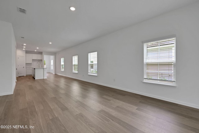 63 Bird Watch Ct, Saint Augustine, FL 32092 - unfurnished living room featuring a sink, light wood-type flooring, baseboards, and recessed lighting