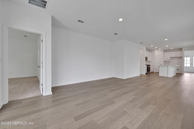 63 Bird Watch Ct, Saint Augustine, FL 32092 - unfurnished living room with light wood-style floors, recessed lighting, baseboards, and a sink