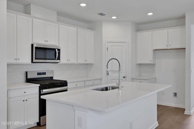 63 Bird Watch Ct, Saint Augustine, FL 32092 - kitchen with stainless steel appliances, a sink, white cabinets, dark wood-style floors, and backsplash