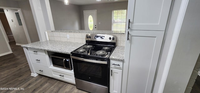 kitchen featuring white cabinetry, light stone counters, appliances with stainless steel finishes, and dark wood-type flooring