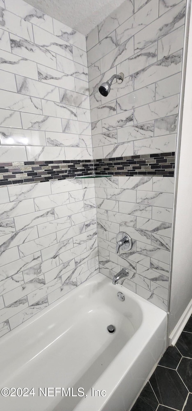 bathroom featuring tiled shower / bath combo and tile patterned flooring