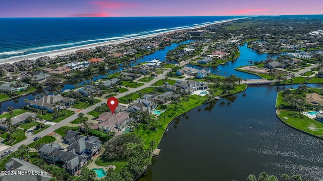 aerial view at dusk featuring a water view and a residential view