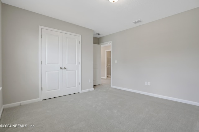 unfurnished bedroom featuring a closet and light colored carpet