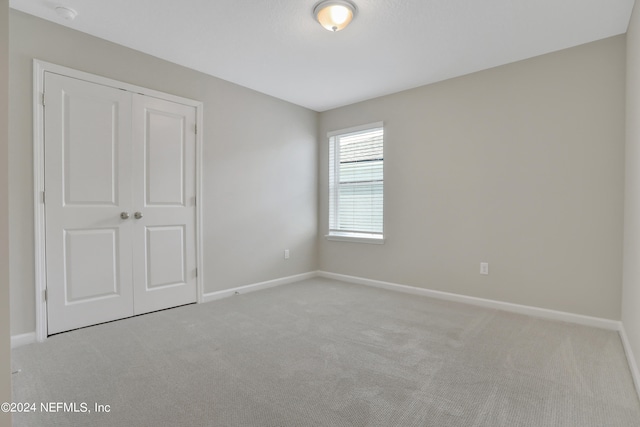 unfurnished bedroom featuring light carpet and a closet