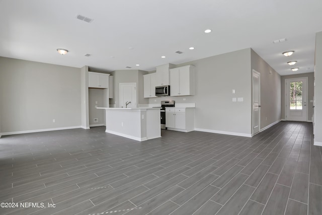 kitchen featuring a center island with sink, wood-type flooring, sink, white cabinetry, and stainless steel appliances