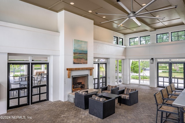 carpeted living room with french doors, a towering ceiling, ceiling fan, and beam ceiling