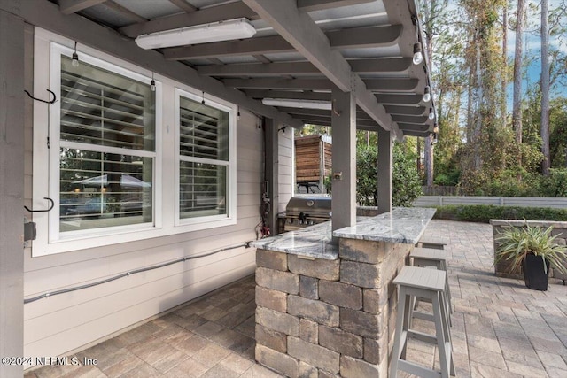 view of patio with area for grilling, a bar, and a grill