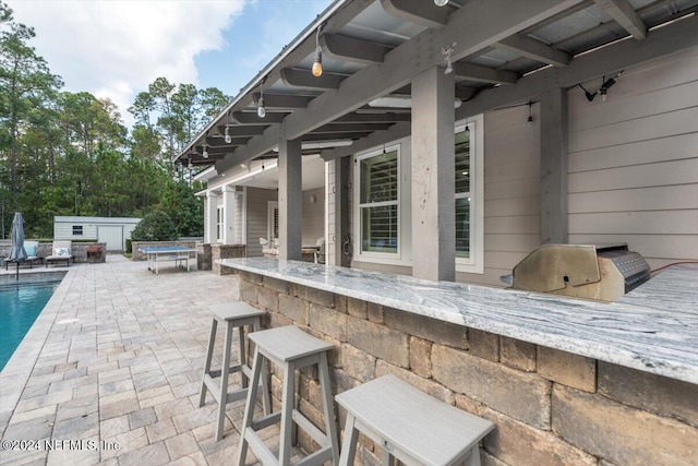 view of patio / terrace with a swimming pool with hot tub and a bar