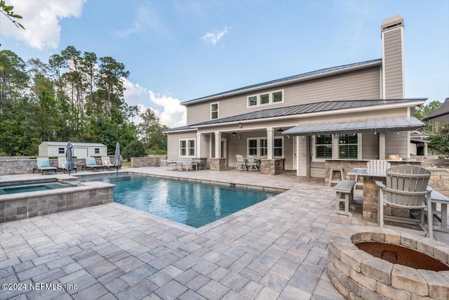 view of pool with a patio, a storage shed, a fire pit, and an in ground hot tub