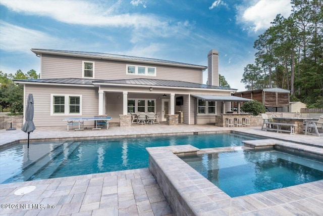 back of house with a patio and a pool with hot tub