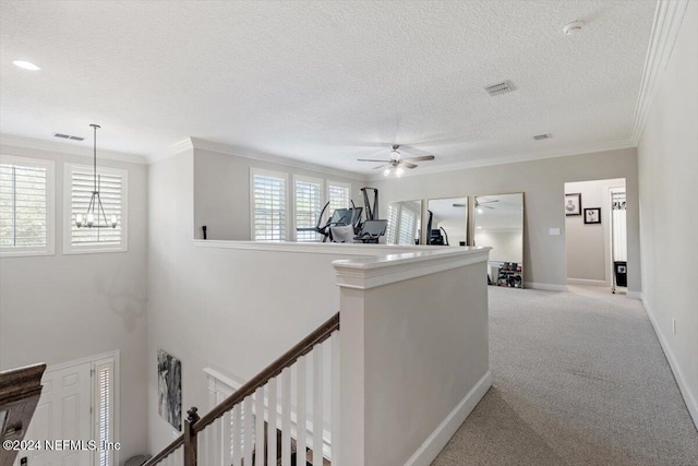 corridor with light carpet, a textured ceiling, plenty of natural light, and ornamental molding