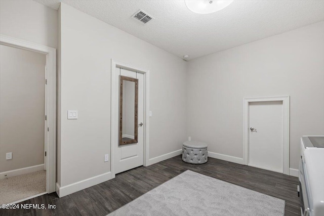 bedroom featuring dark hardwood / wood-style floors, a textured ceiling, and separate washer and dryer