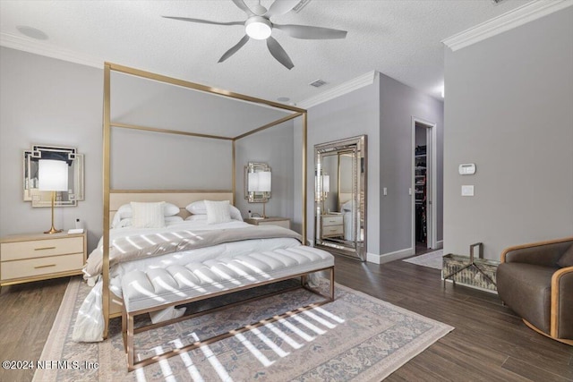 bedroom with ceiling fan, a textured ceiling, dark hardwood / wood-style flooring, and a walk in closet