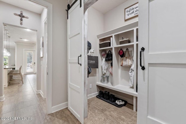 mudroom featuring a textured ceiling, light tile patterned floors, and a barn door