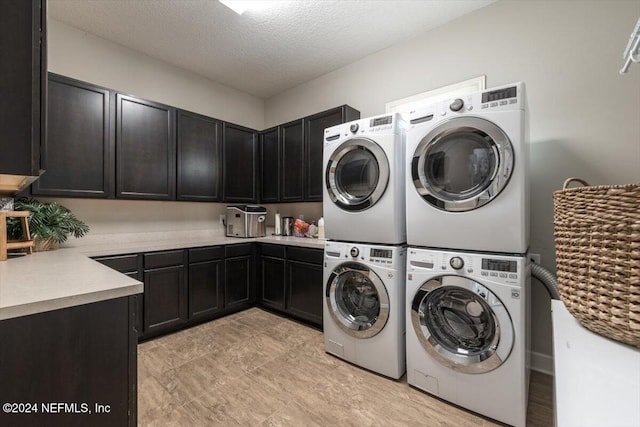 washroom with cabinets, a textured ceiling, stacked washer and dryer, and washer and dryer