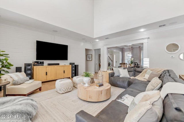 living room featuring a towering ceiling, crown molding, and light wood-type flooring