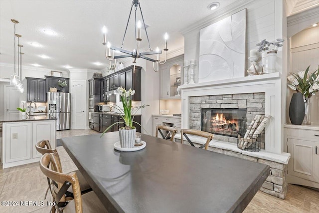 dining area with a stone fireplace, ornamental molding, a textured ceiling, and light wood-type flooring