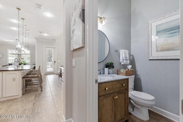 bathroom with toilet, tile patterned flooring, ornamental molding, vanity, and a textured ceiling