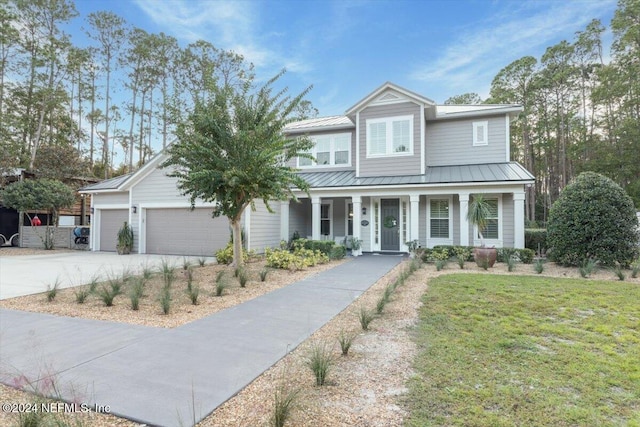 view of front of home featuring covered porch, a garage, and a front lawn