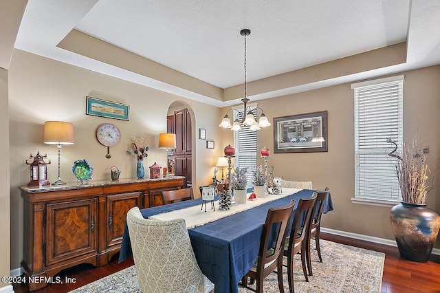 dining room featuring an inviting chandelier, dark hardwood / wood-style floors, and a tray ceiling