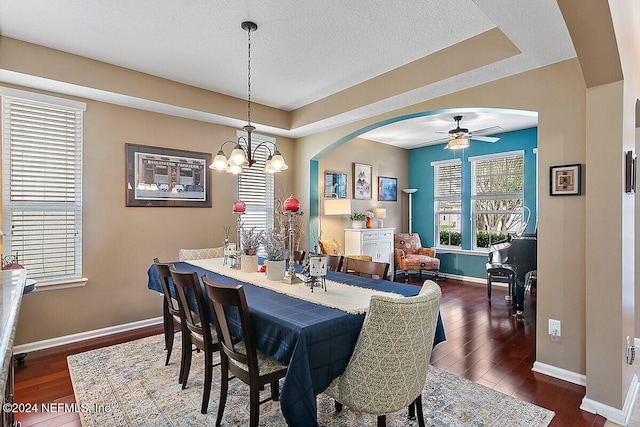 dining area with dark wood-type flooring, a textured ceiling, and ceiling fan with notable chandelier