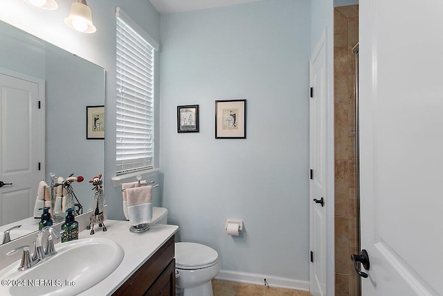 bathroom featuring vanity, a tile shower, and toilet