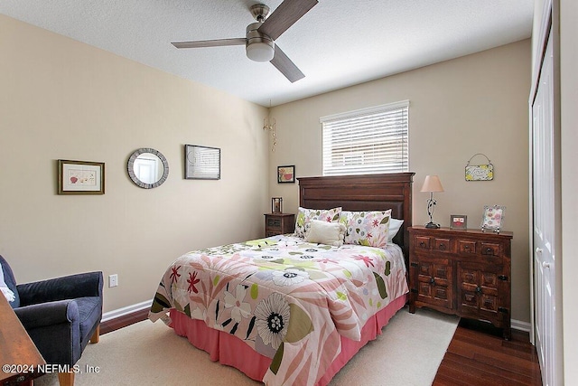 bedroom featuring dark wood-type flooring, ceiling fan, a closet, and a textured ceiling