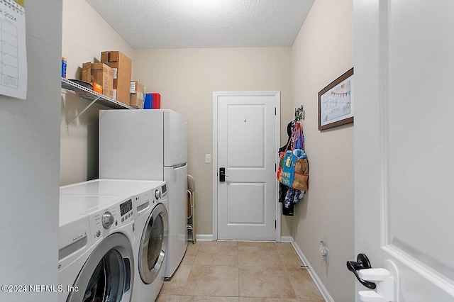 washroom with independent washer and dryer, a textured ceiling, and light tile patterned floors