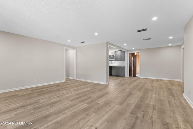 unfurnished living room featuring light hardwood / wood-style flooring and a textured ceiling