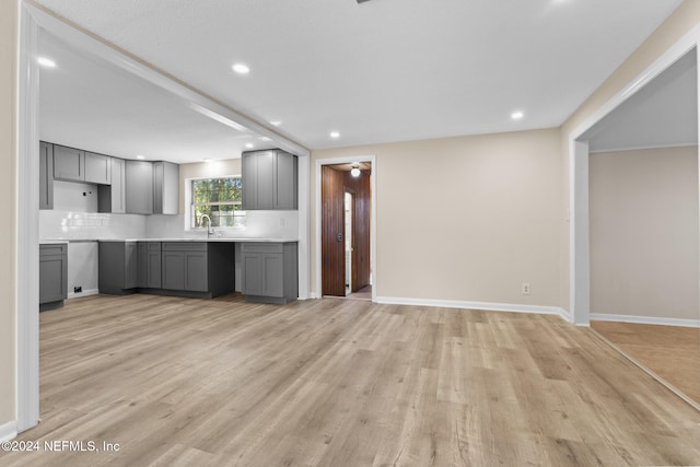 kitchen with light hardwood / wood-style flooring, decorative backsplash, sink, and gray cabinetry