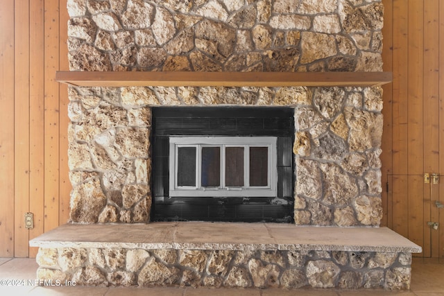 room details featuring wood walls, tile patterned flooring, and a stone fireplace