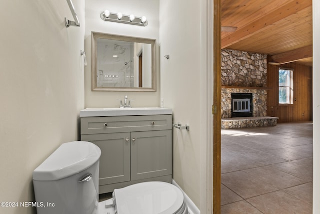 bathroom with tile patterned floors, toilet, wooden ceiling, vanity, and a fireplace