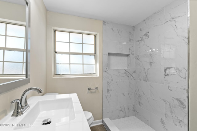 bathroom with toilet, vanity, and tiled shower