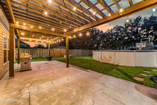 patio terrace at dusk with a pergola, a lawn, and a pool