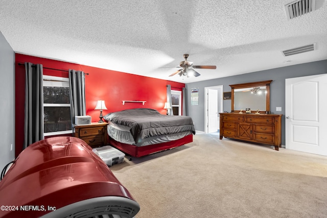 carpeted bedroom featuring multiple windows, ceiling fan, and a textured ceiling