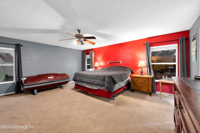 bedroom featuring a textured ceiling, light colored carpet, and ceiling fan