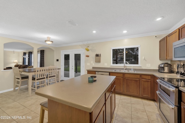 kitchen with french doors, stainless steel appliances, sink, ornamental molding, and a kitchen island